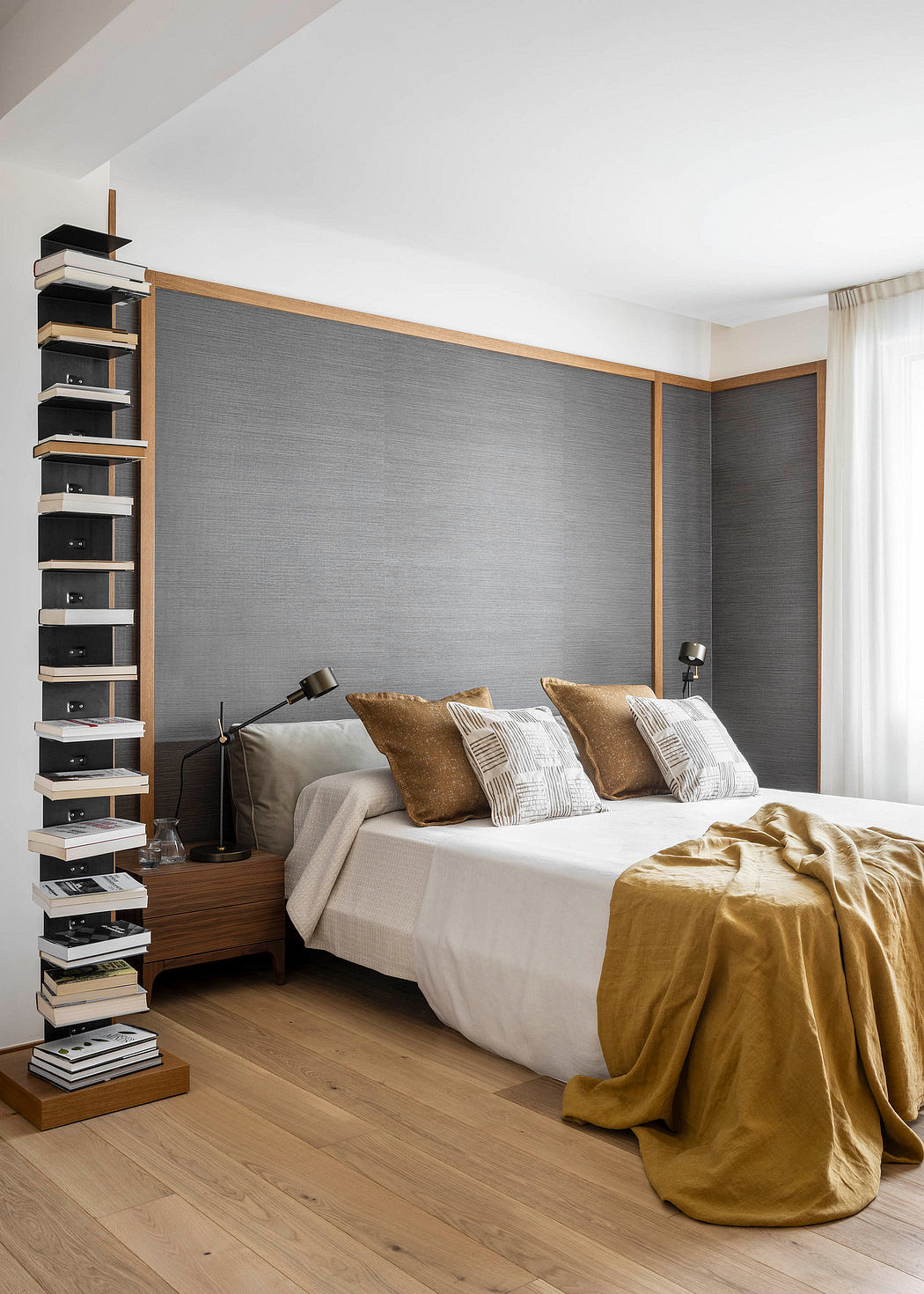 Minimalist bedroom with built-in shelving, gray accent wall, and warm textiles.