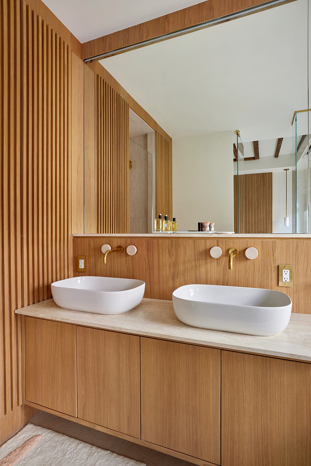 A modern bathroom with a wooden vanity, dual vessel sinks, and a striking wood paneled wall.