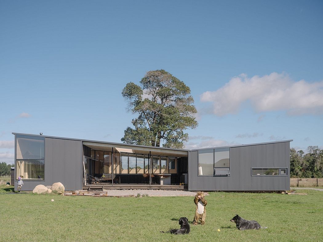 Modern modular home with expansive windows, surrounded by lush greenery and rocks.