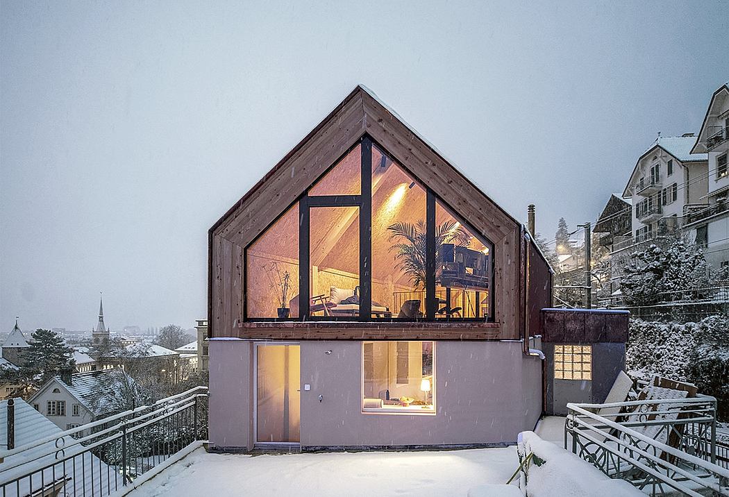 A cozy modern cabin home nestled in a snowy landscape, featuring an A-frame design with large windows.