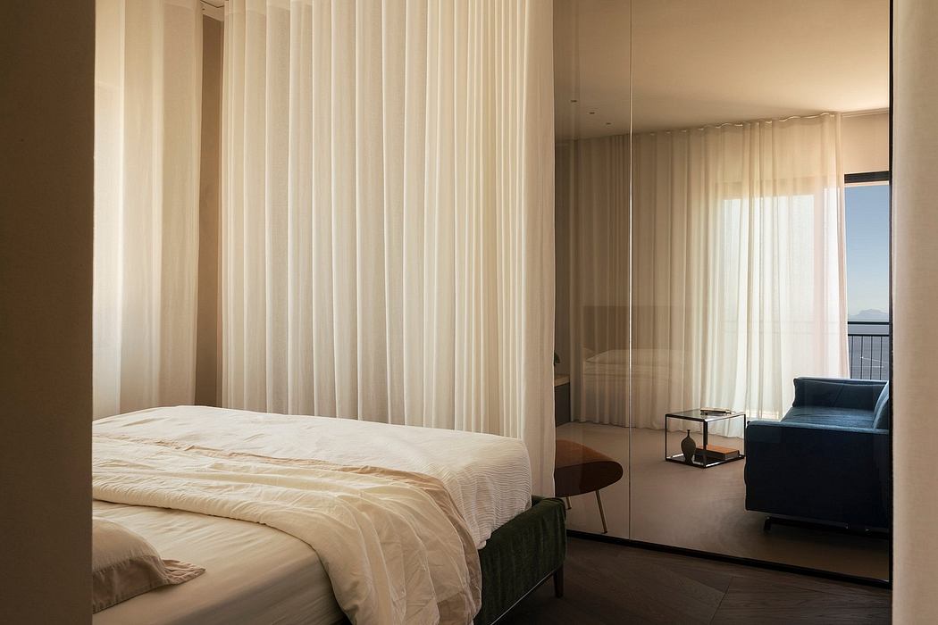 Spacious hotel room with plush bedding, sheer curtains, and a cozy seating area.