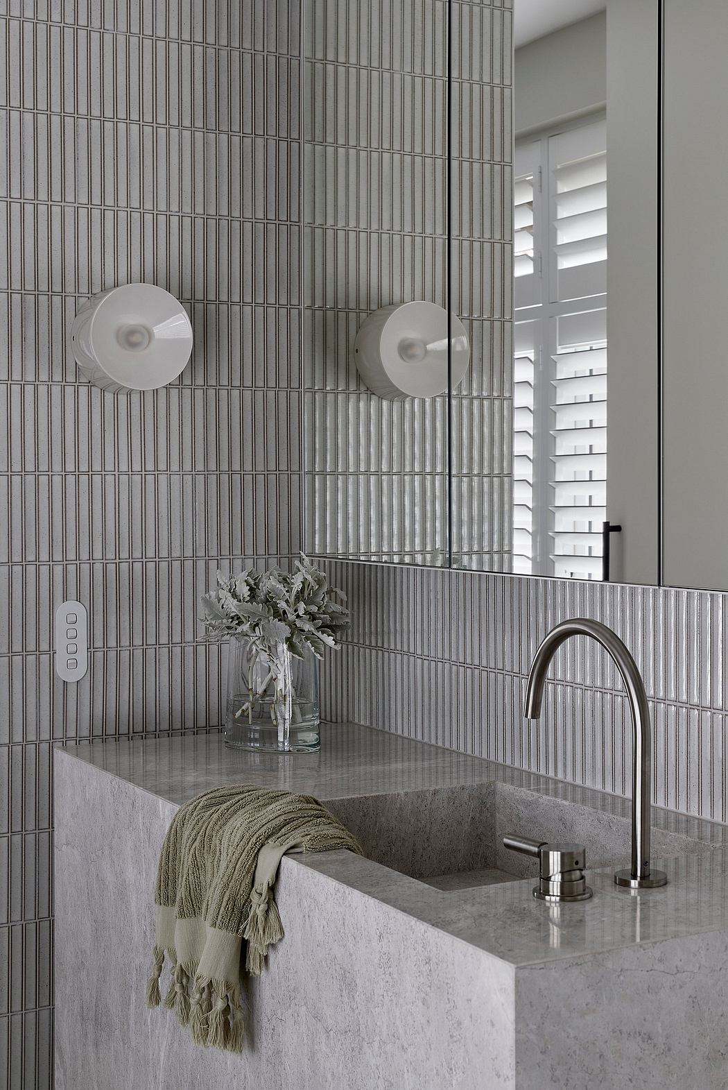 Modern bathroom with sleek gray tile, marble counter, and minimalist fixtures.