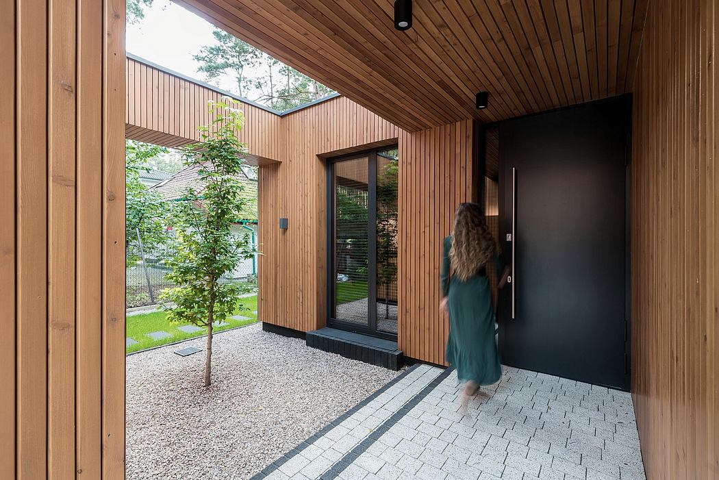 A modern, wood-paneled entryway leads to a lush, green yard through a glass door.