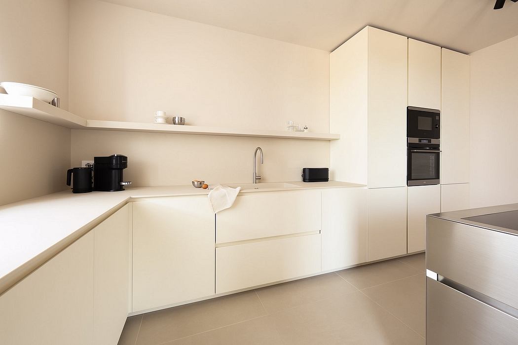 Modern kitchen with clean, minimalist design featuring white cabinets, open shelving, and integrated appliances.