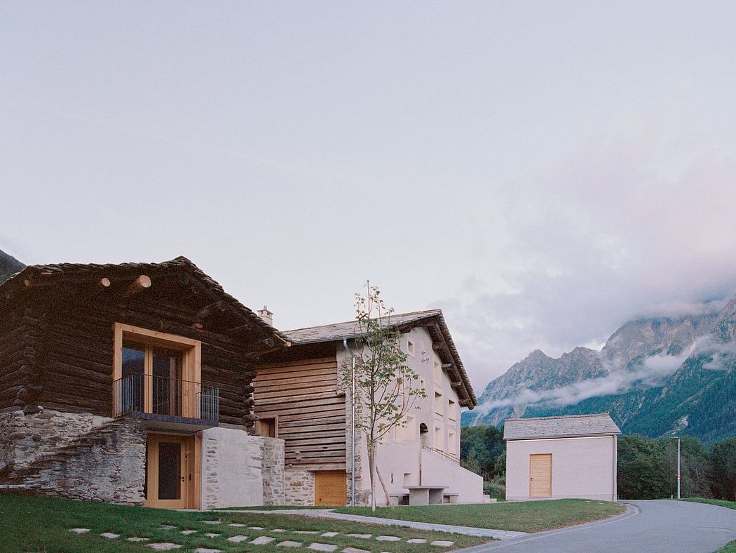 Rustic mountain lodge with timber frame construction, stone accents, and lush grassy surrounds.