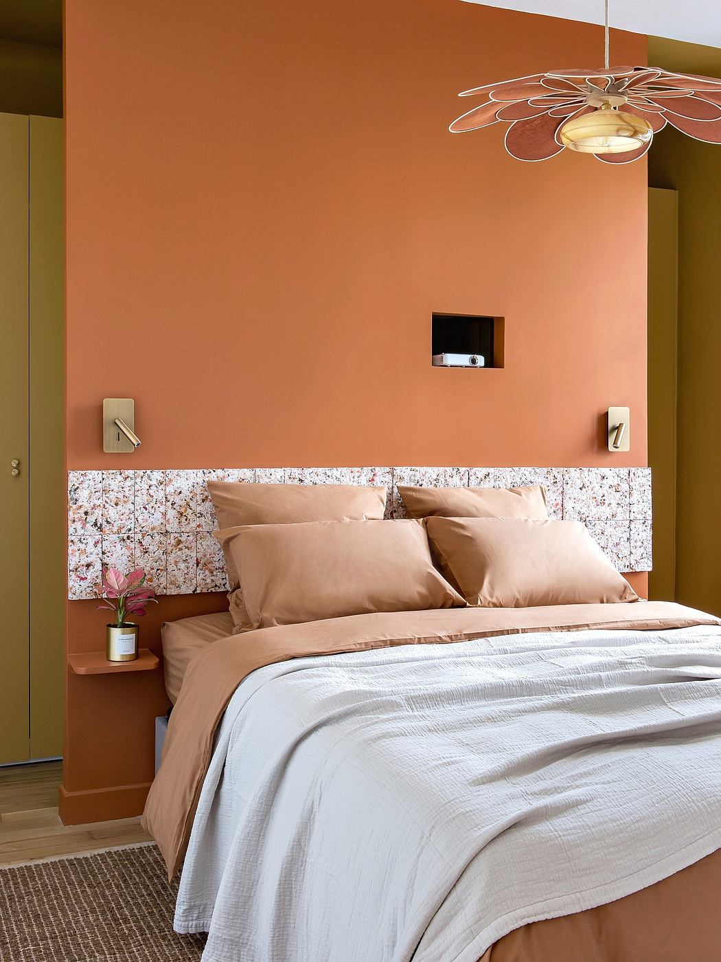 Warm-toned bedroom with unique floral light fixture and patterned headboard.