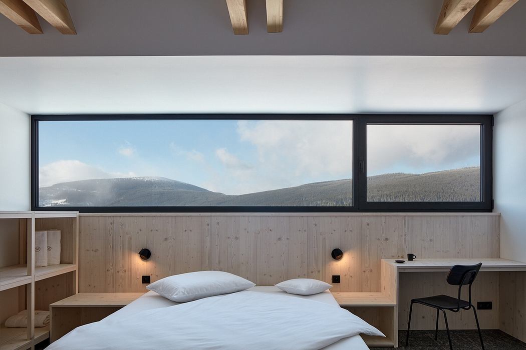 Large windows offer panoramic mountain views in this modern, wood-paneled bedroom.