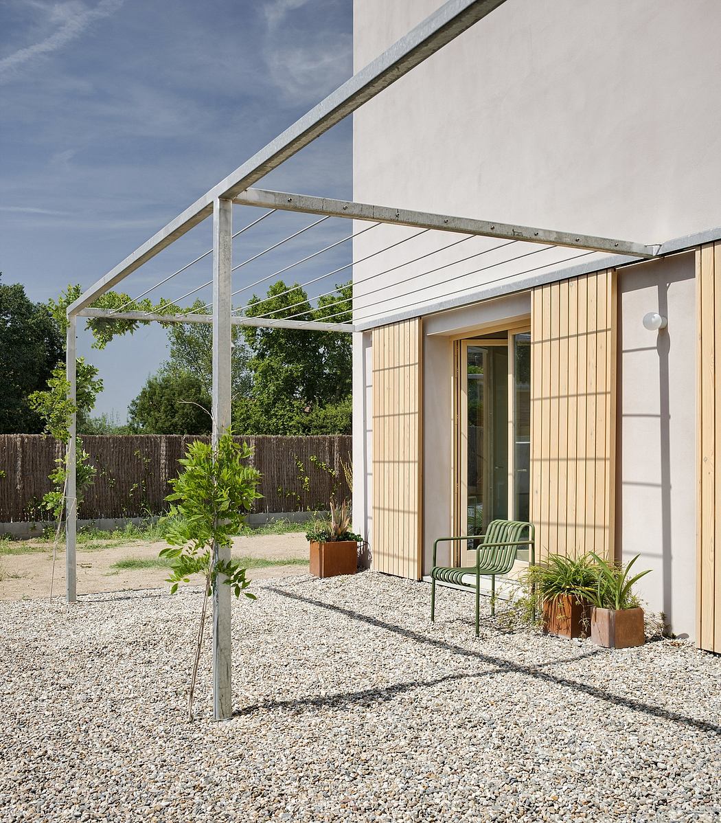 Modern outdoor patio with steel frame canopy, wooden siding, and gravel floor.