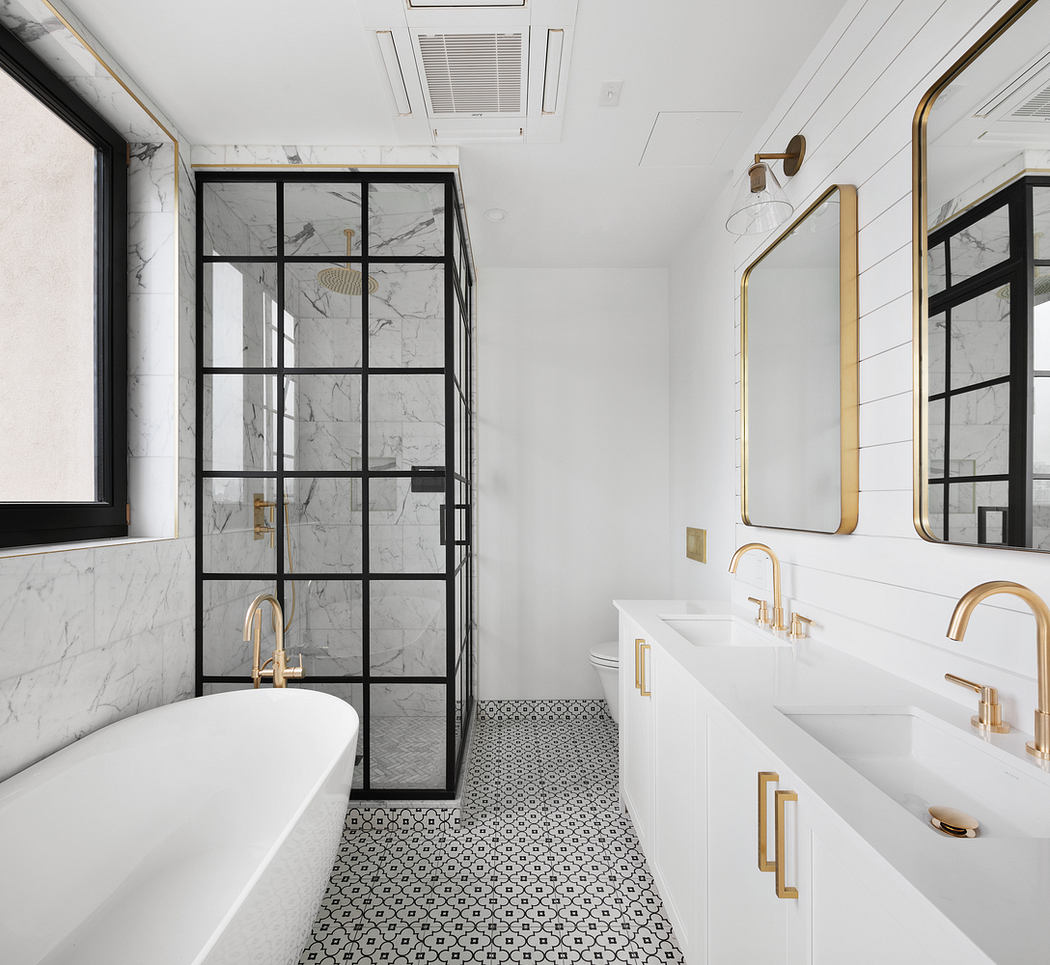 Luxurious bathroom with marble walls, black-framed glass shower, gold fixtures.