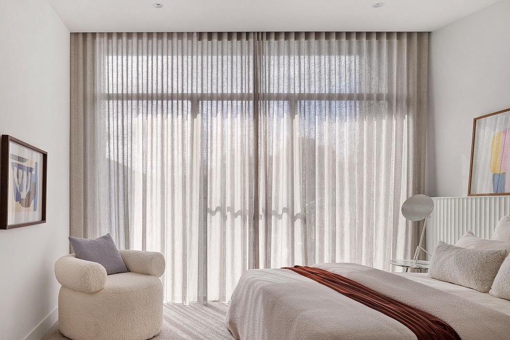 Modern bedroom with large windows, flowing curtains, and minimalist furnishings.