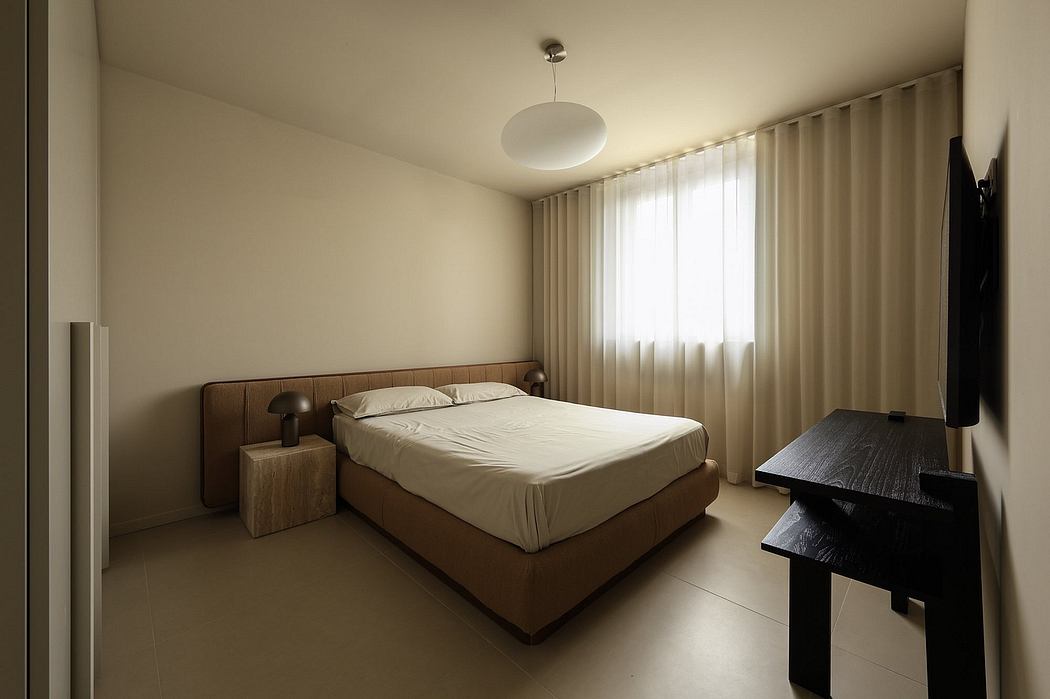 A minimalist bedroom with a simple, modern bed frame and dark accent furniture.