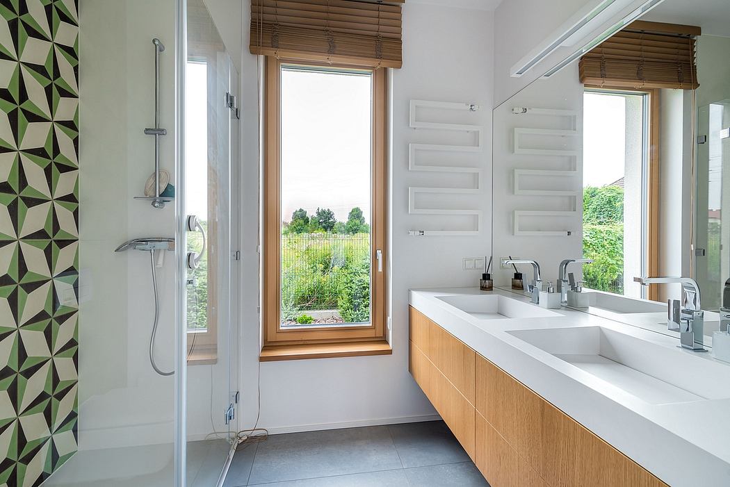 Modern bathroom with wood-framed window, dual vanity, and patterned tile wall.