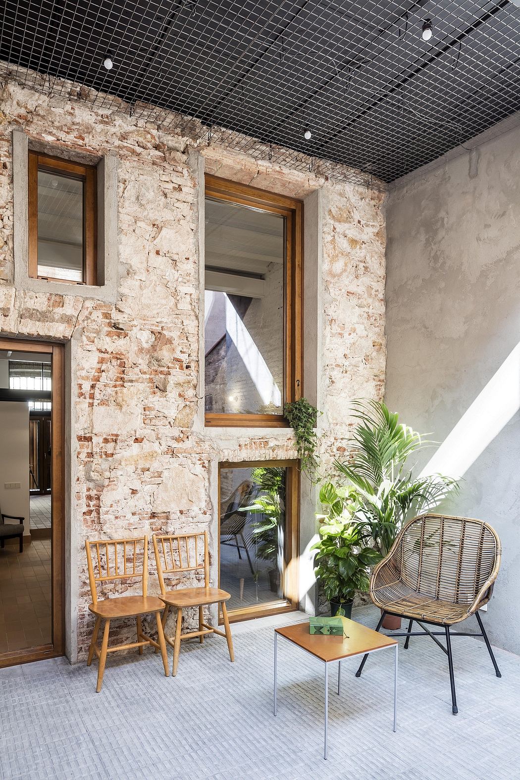 Rustic stone walls, wooden furniture, and lush greenery highlight the cozy interior design.