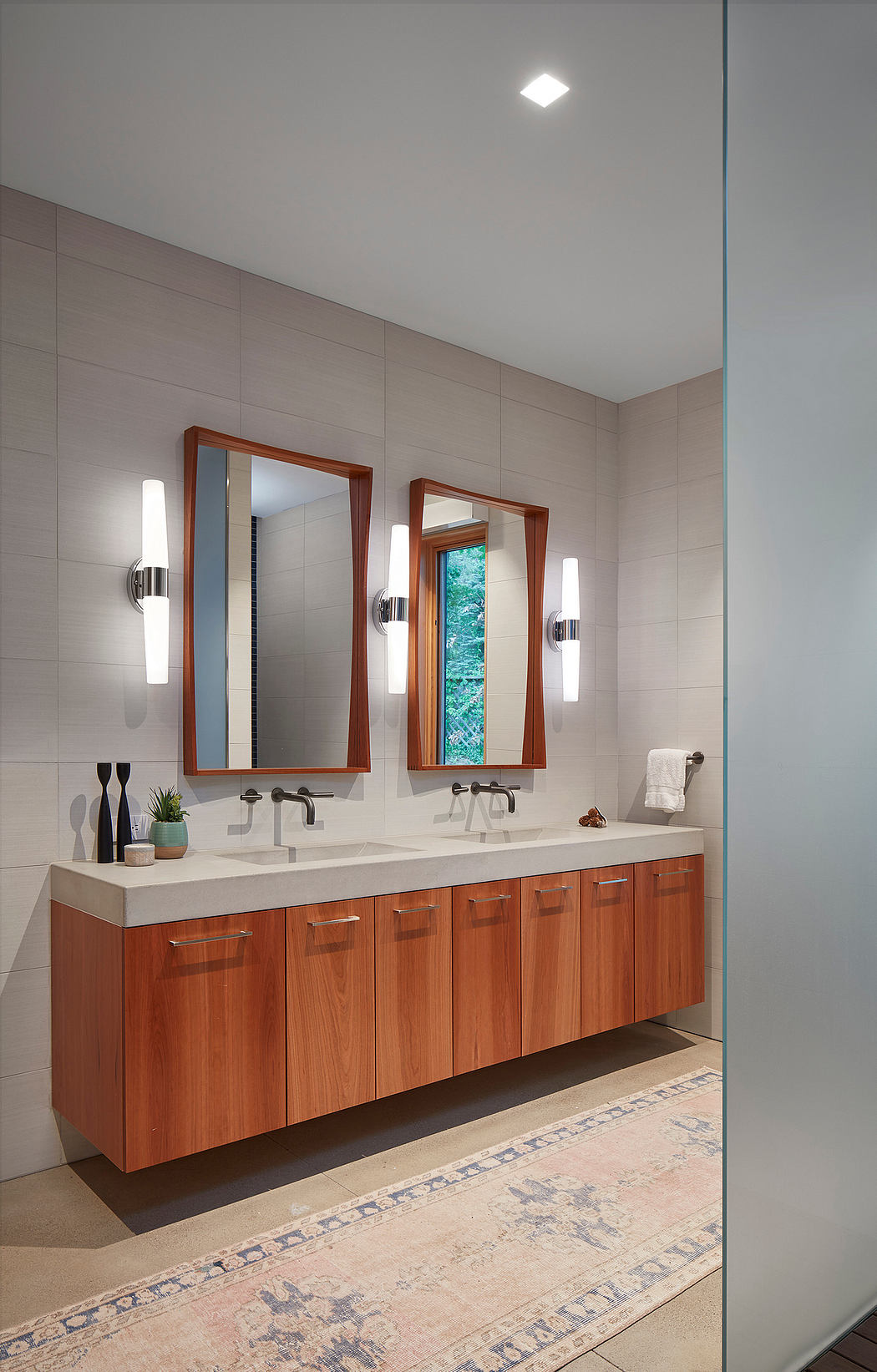 Modern bathroom with wooden vanity, double mirrors, and recessed lighting.