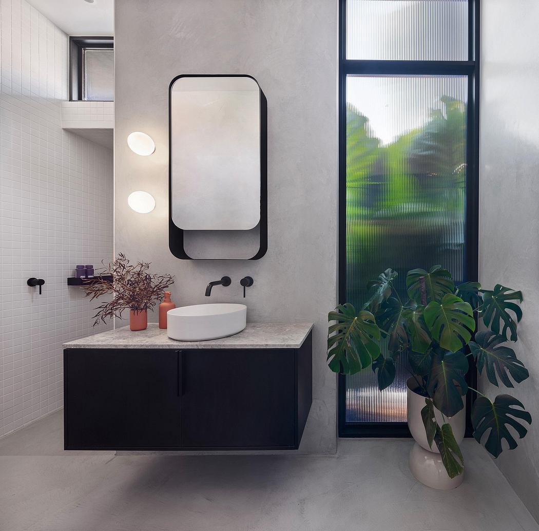 A minimalist bathroom with a modern vanity, circular mirror, and lush tropical plants.