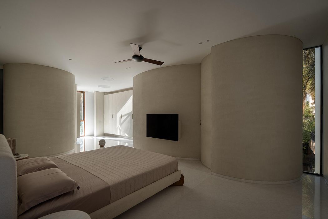 Spacious, modern bedroom with curved walls, large windows, and minimalist furnishings.