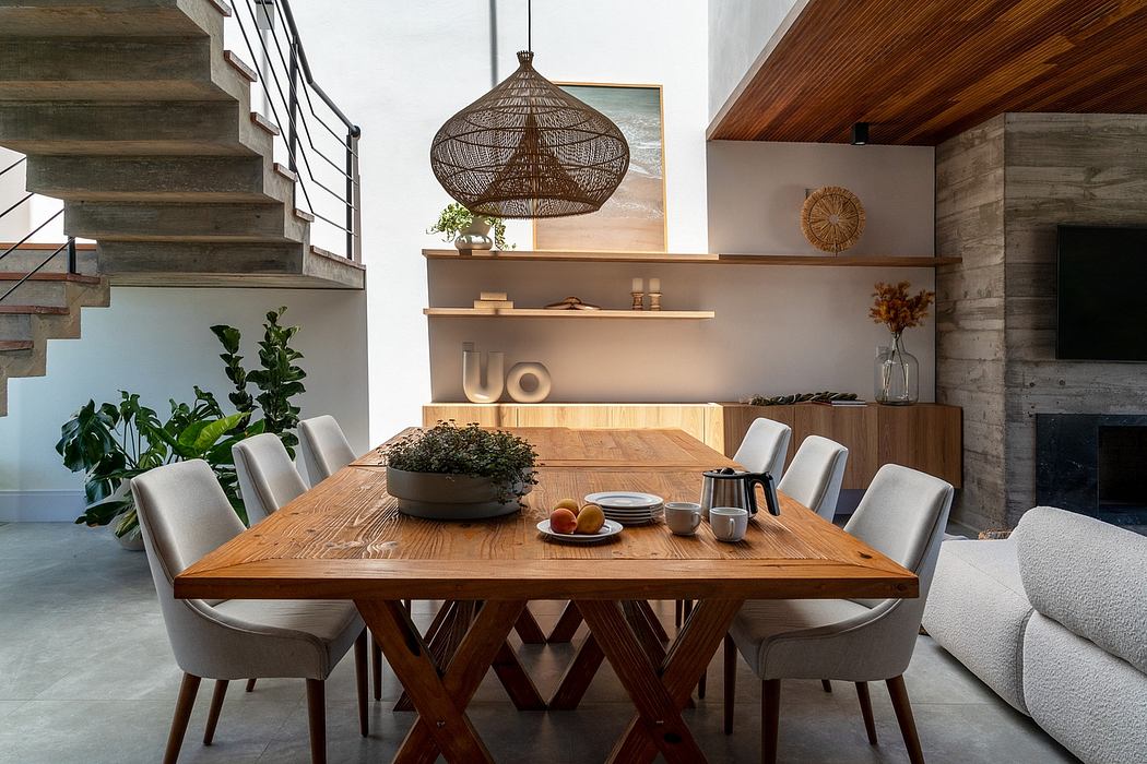 Rustic wooden dining table with plush chairs, pendant light, and neatly organized shelves.