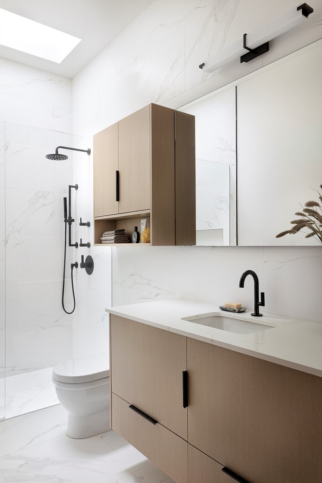 A modern bathroom with sleek, minimalist design featuring wooden cabinetry, black fixtures, and a marble-like tile floor.