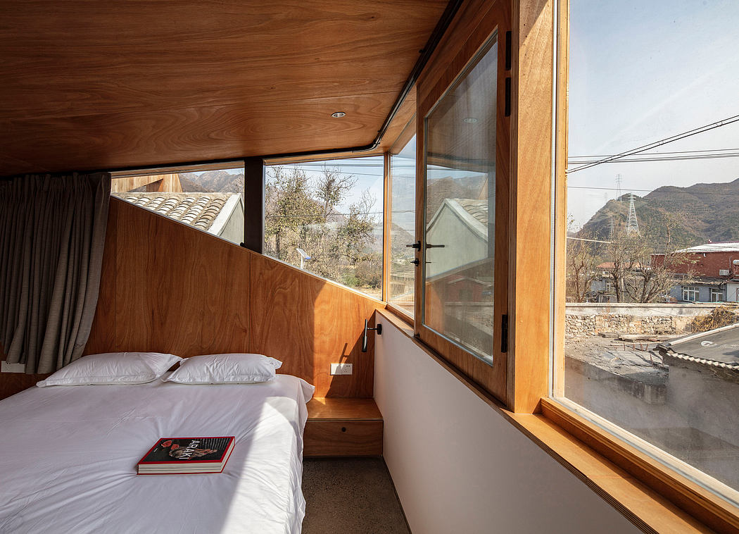 A cozy bedroom with wooden walls, large windows, and a scenic mountain view.