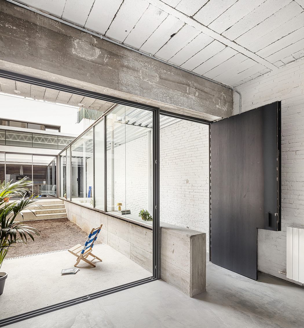 Minimalist interior with concrete walls, expansive windows, and a small deck chair.