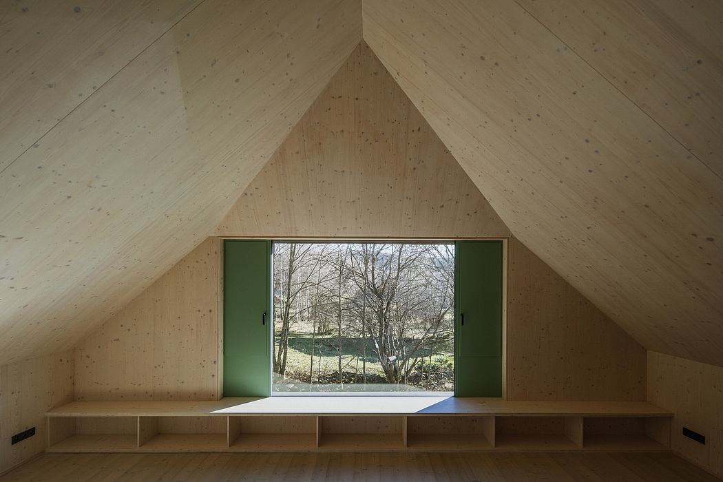 A modern, minimalist interior with a slanted wooden ceiling, built-in shelves, and large green doors that open to the outdoors.