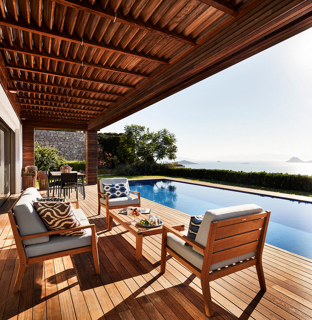 Expansive wooden deck with seating, pool, and scenic ocean backdrop framed by thatched roof.
