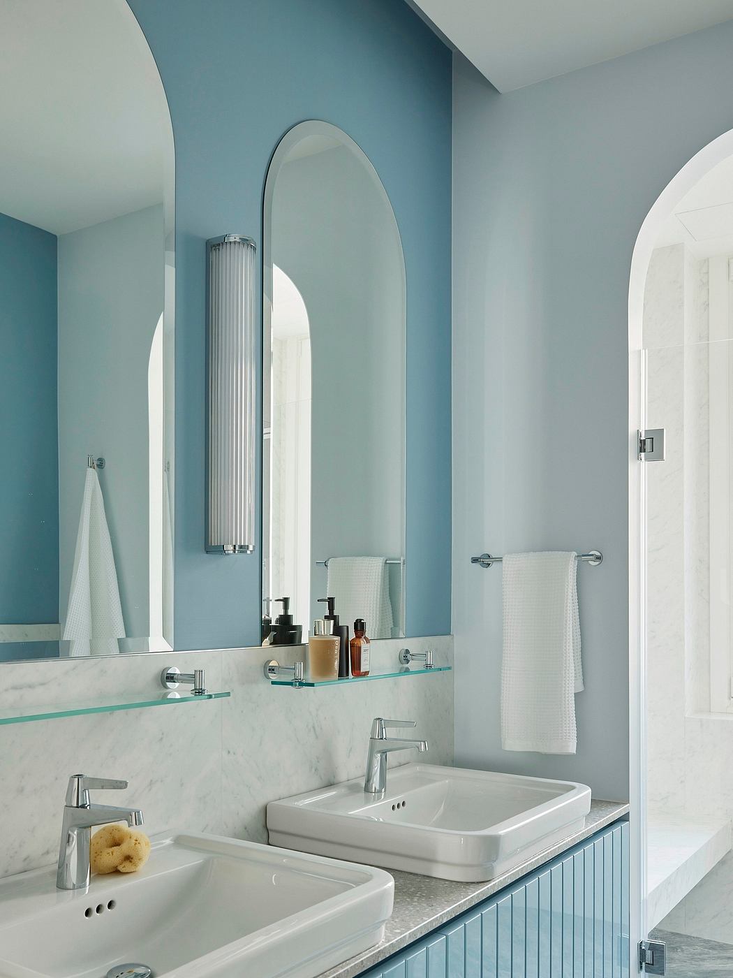 Modern bathroom with arched mirrors, marble vanity, and a chrome radiator.
