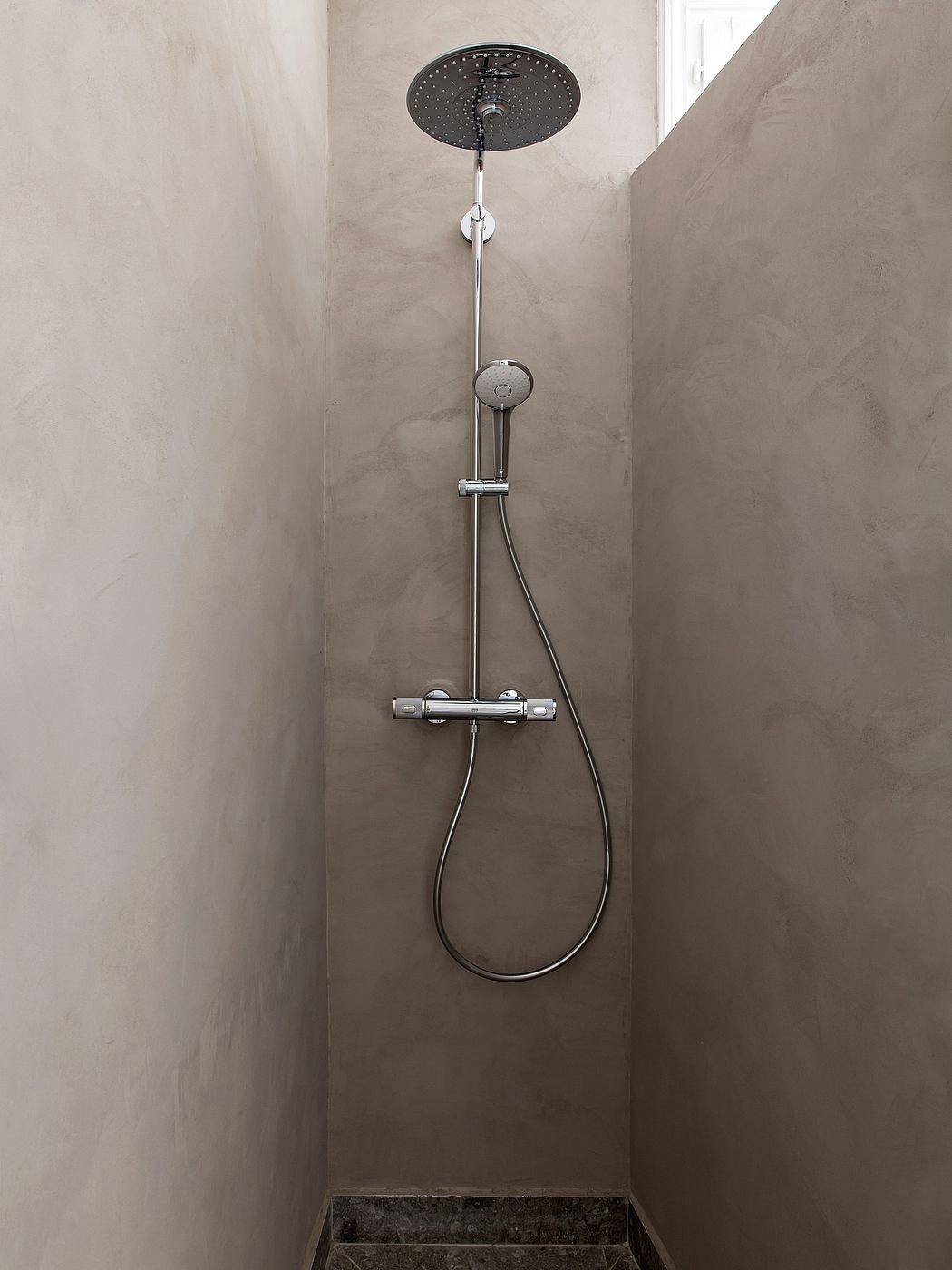 Modern shower with sleek, minimalist design featuring a black rain showerhead and chrome fixtures.