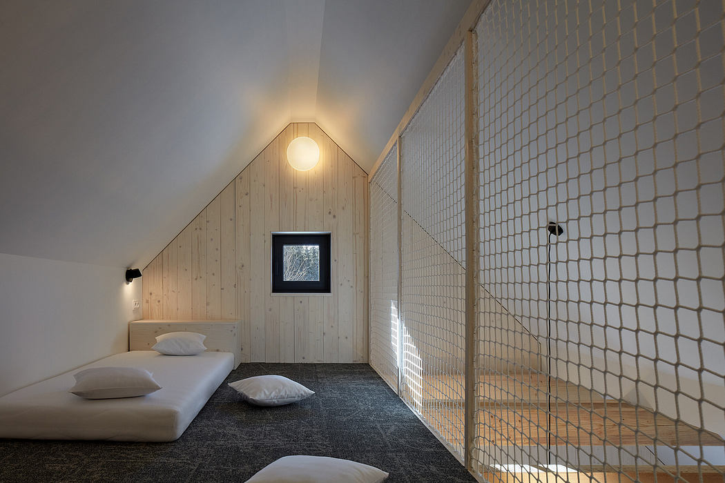 Cozy loft bedroom with slanted ceiling, wooden walls, and modern metal railing divider.