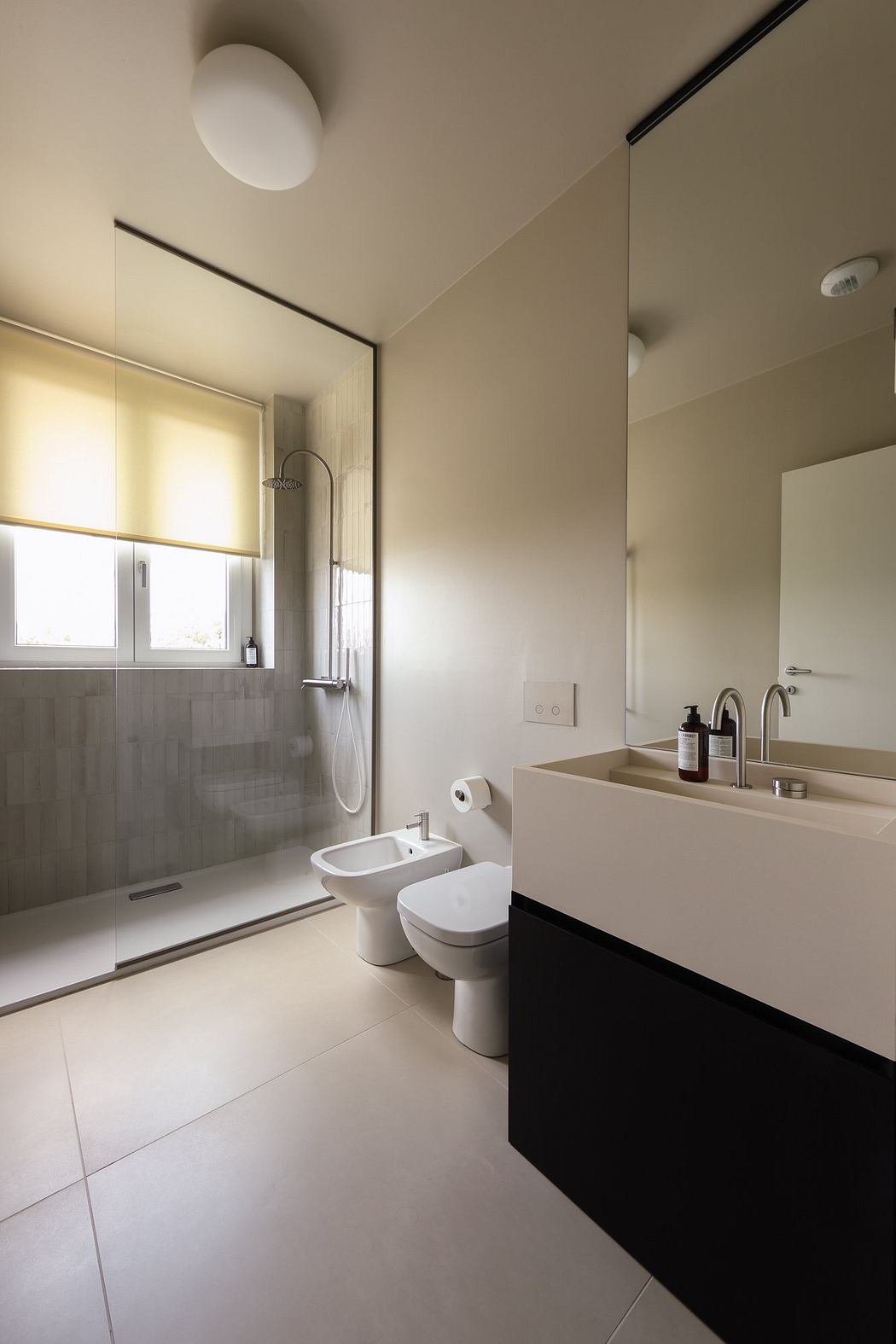 Minimalist bathroom design with tiled walls, floating vanity, and recessed lighting.