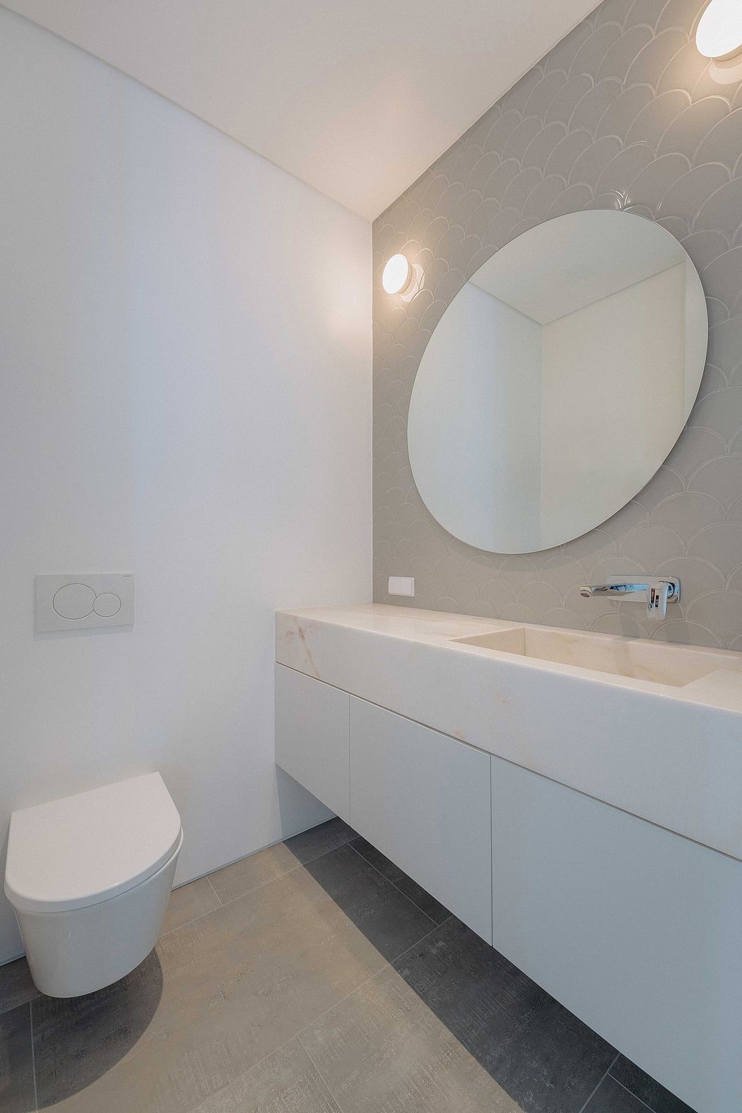 Minimalist bathroom design with white vanity, round mirror, and patterned accent wall.