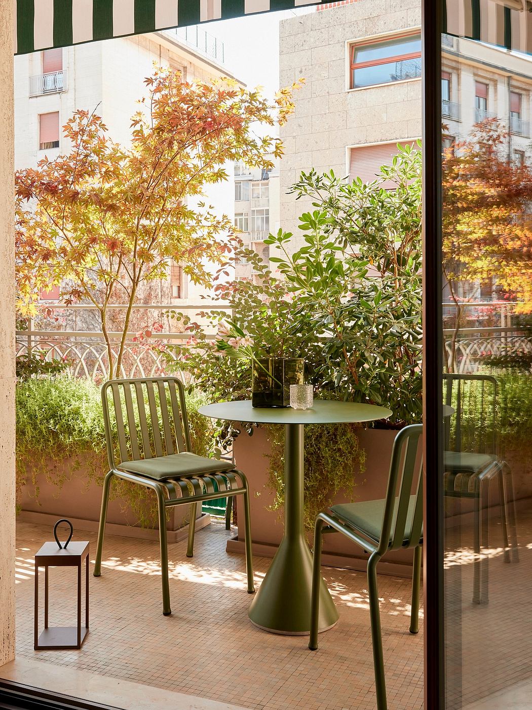 Vibrant autumn foliage frames a cozy outdoor cafe setting with metal furniture and plants.