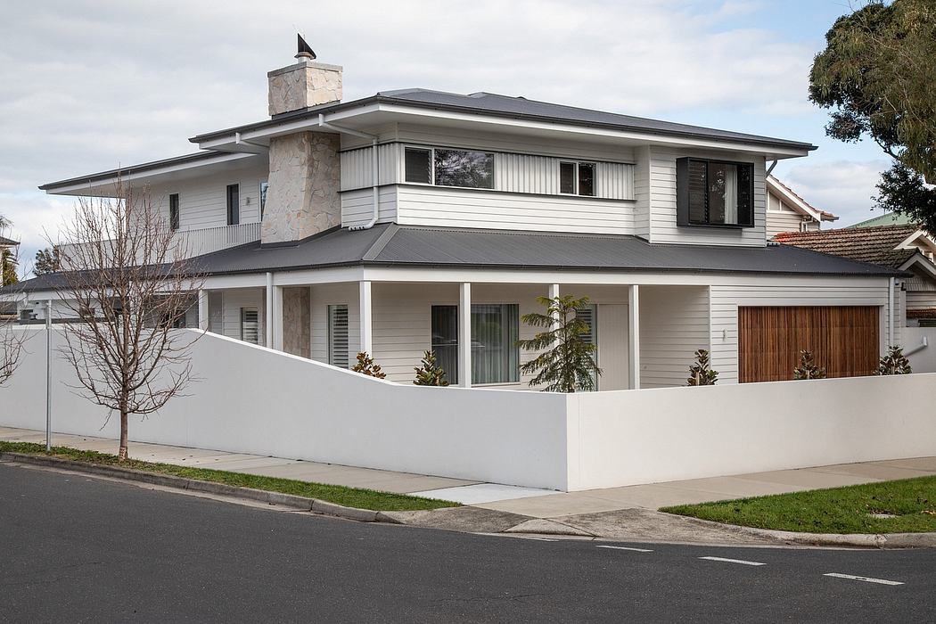 Modern two-story residential home with gray siding, stone chimney, and decorative roof details.