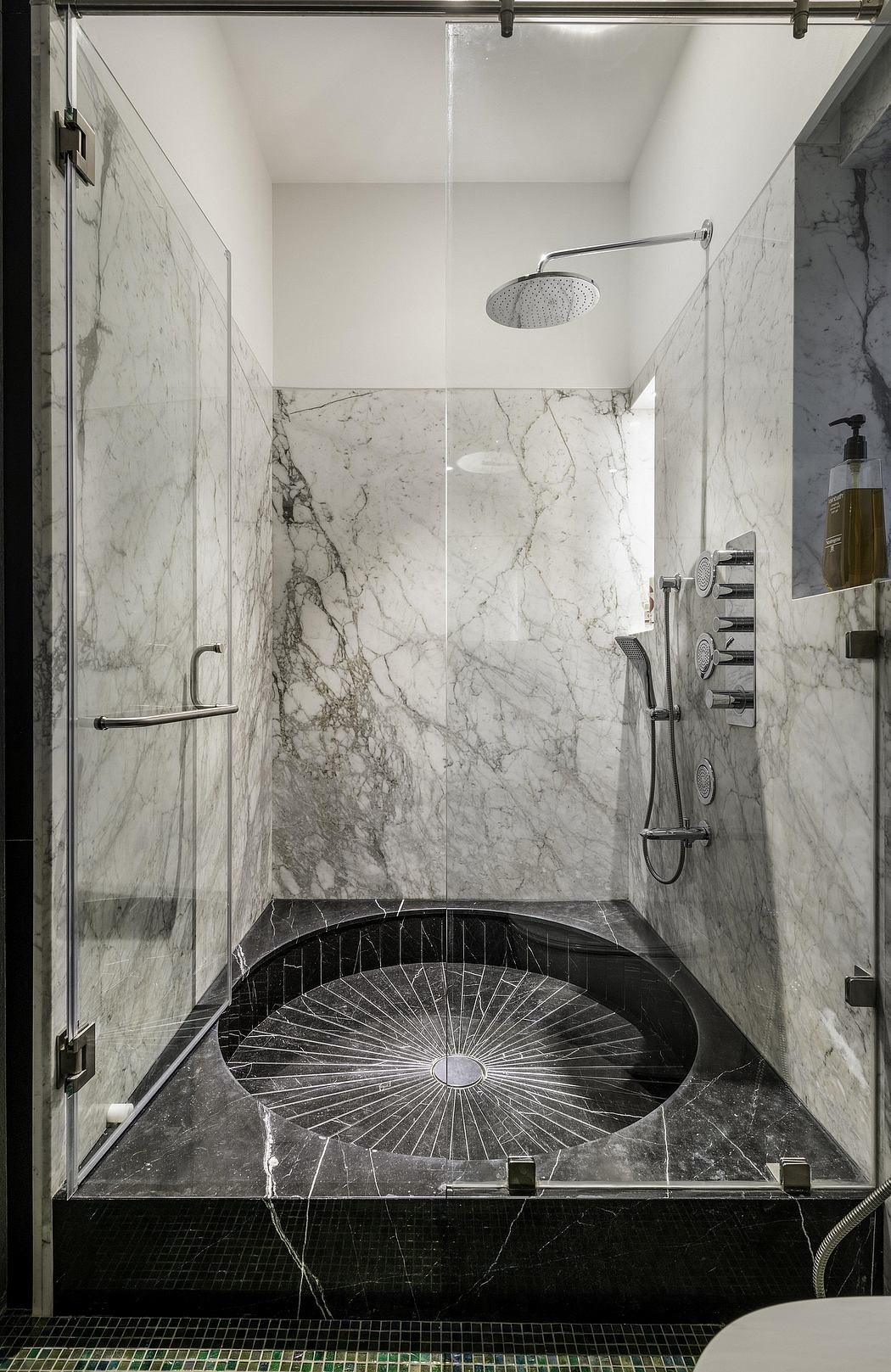 Sleek, modern bathroom with floor-to-ceiling marble walls, sunburst-patterned shower, and minimalist fixtures.
