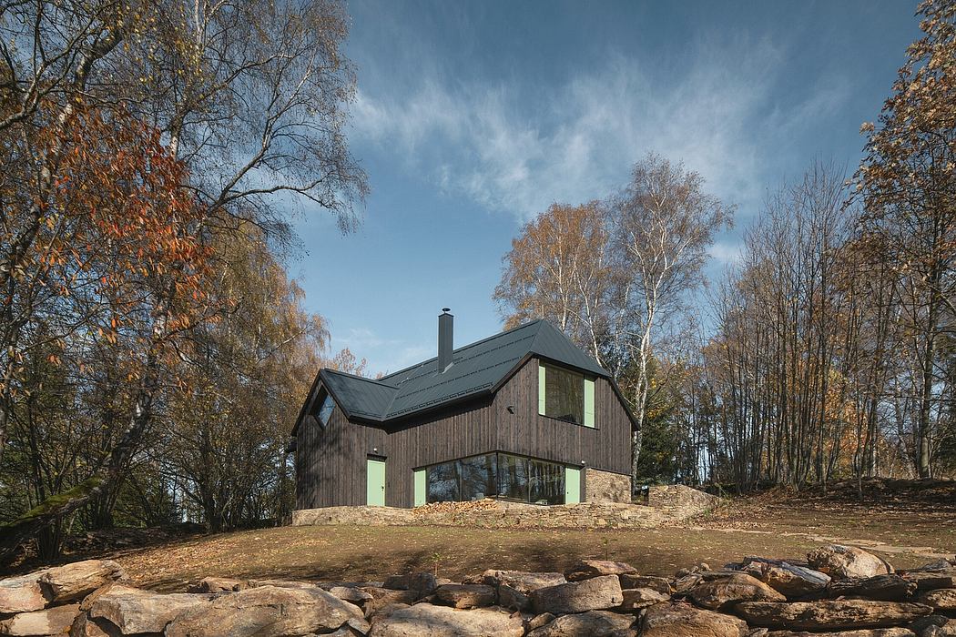 A modern, wooden cabin nestled in a forested landscape with floor-to-ceiling windows.