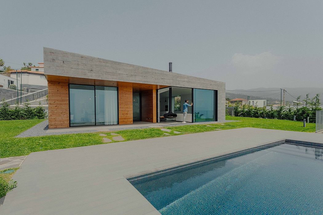 A modern, minimalist house with a pool, glass walls, and a grassy yard.