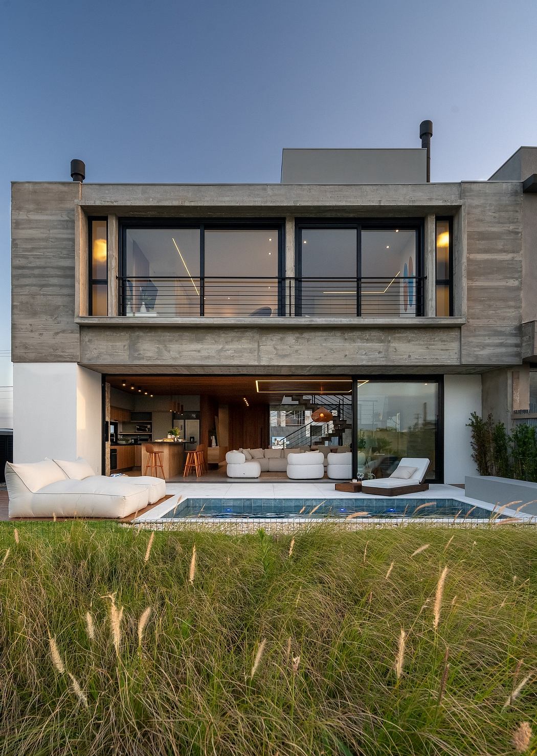 Sleek, modern architecture with expansive glass windows, outdoor seating, and a pool.