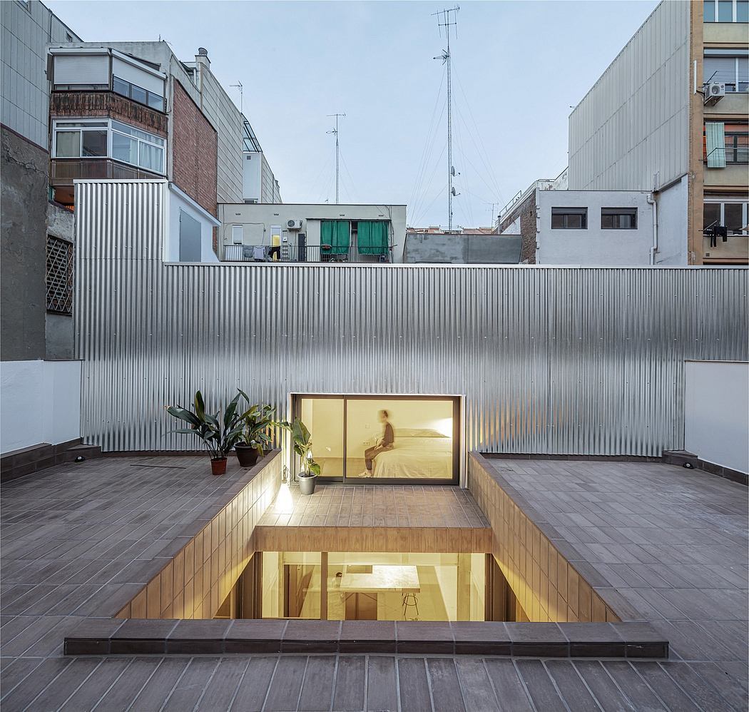 Outdoor patio with recessed seating area and large glass window revealing interior.