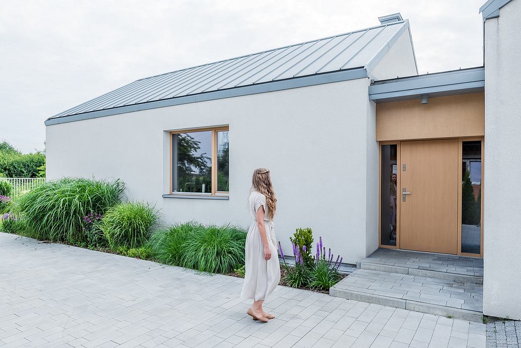 Modern building exterior with slanted metal roof, large windows, and landscaped garden.