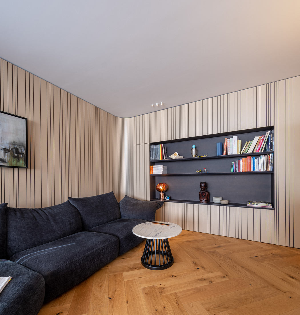 Minimalist living room with wooden floors, built-in shelving, and dark sofa.