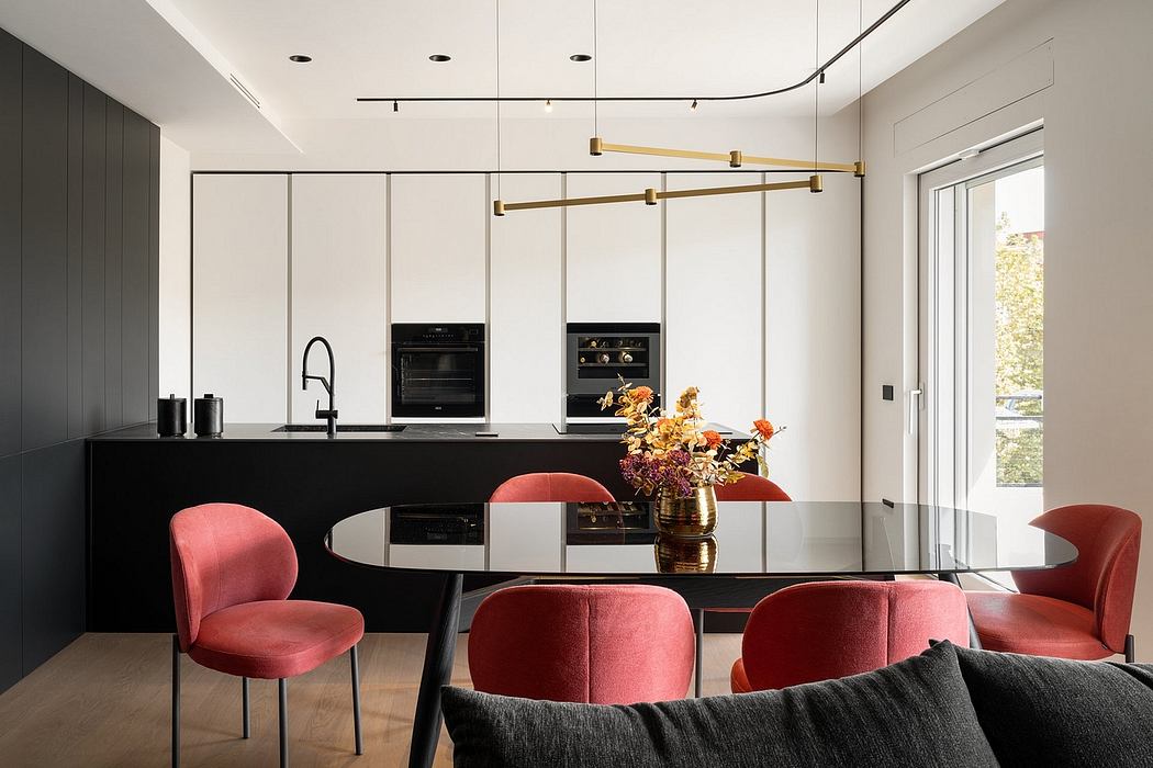 Sleek, modern kitchen with black cabinets, gold accents, and bright red upholstered chairs.