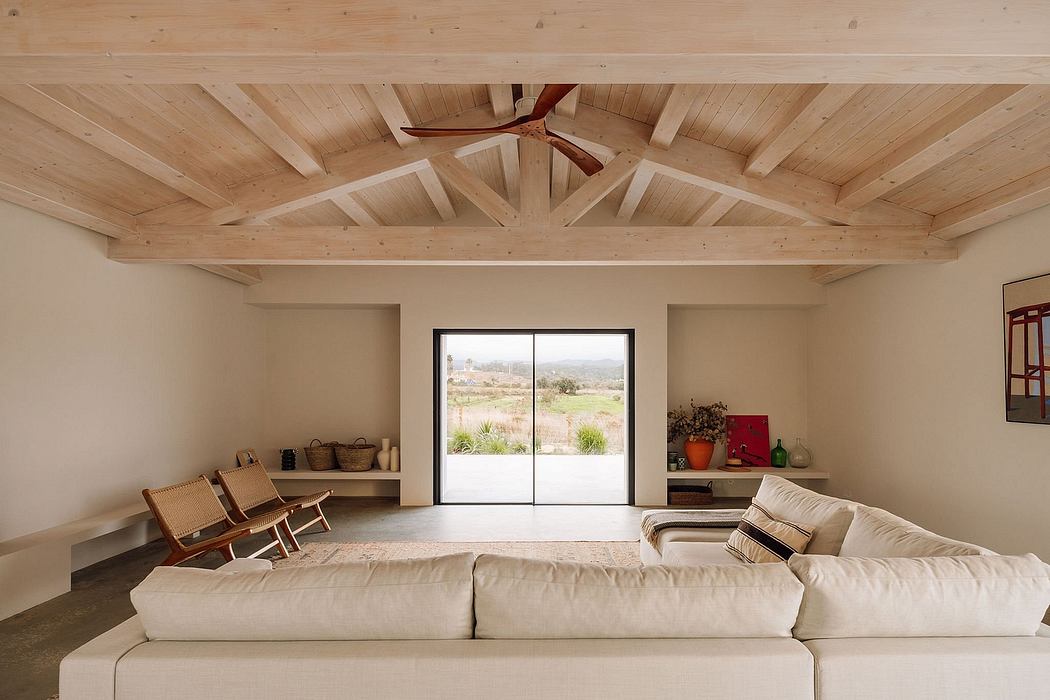 A spacious living room with a high, wooden-beamed ceiling and large sliding glass doors.