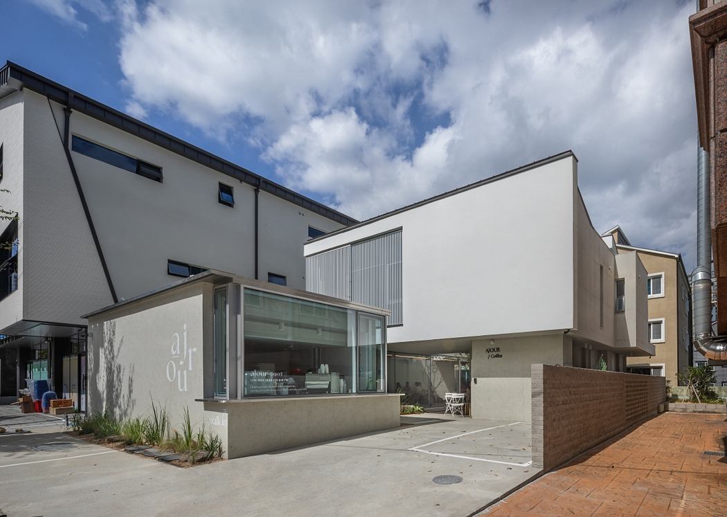 Modern mixed-use building with glass facade, striped panels, and courtyard entry.