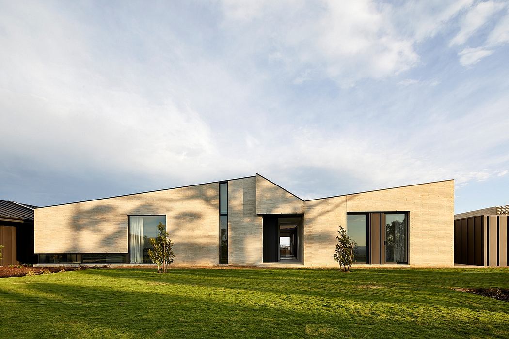 A modern, minimalist building with clean lines, large windows, and surrounded by a lush green lawn.