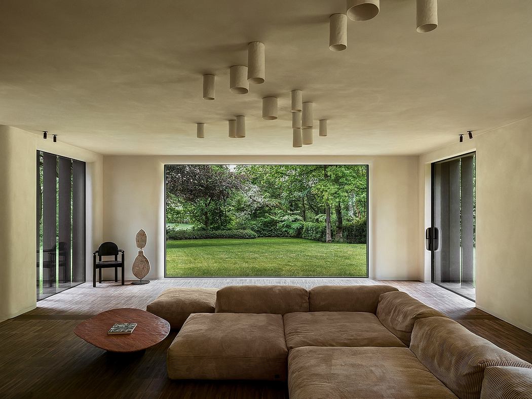 A modern living room with a large window overlooking a lush green outdoor scene, accented by distinctive pendant lighting.