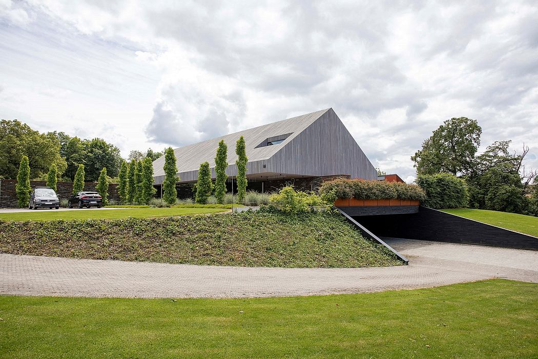 A modern, gray-toned building with a distinctive slanted roof and landscaped surroundings.