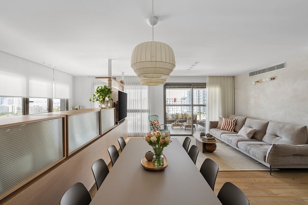 Modern, open-concept living room with sleek furnishings, floor-to-ceiling windows, and a striking pendant light.