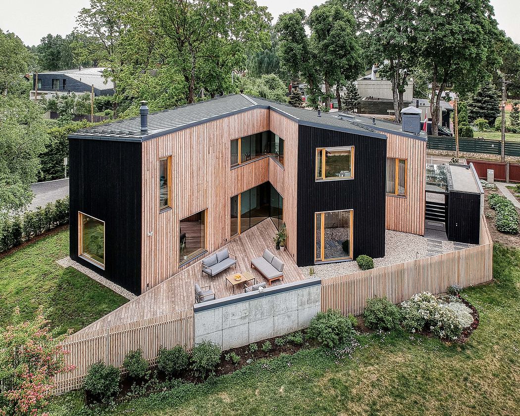 Modern, wood-clad home with sleek, angular design and large windows overlooking a garden.