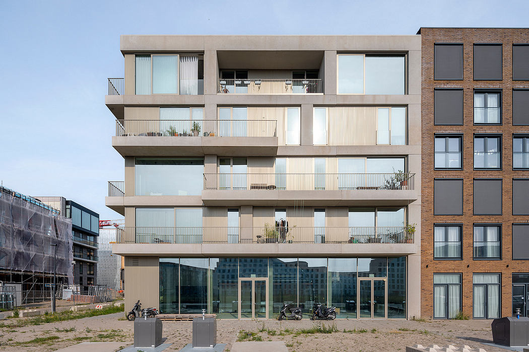 Modern multi-story apartment building with glass facades, balconies, and street-level retail space.