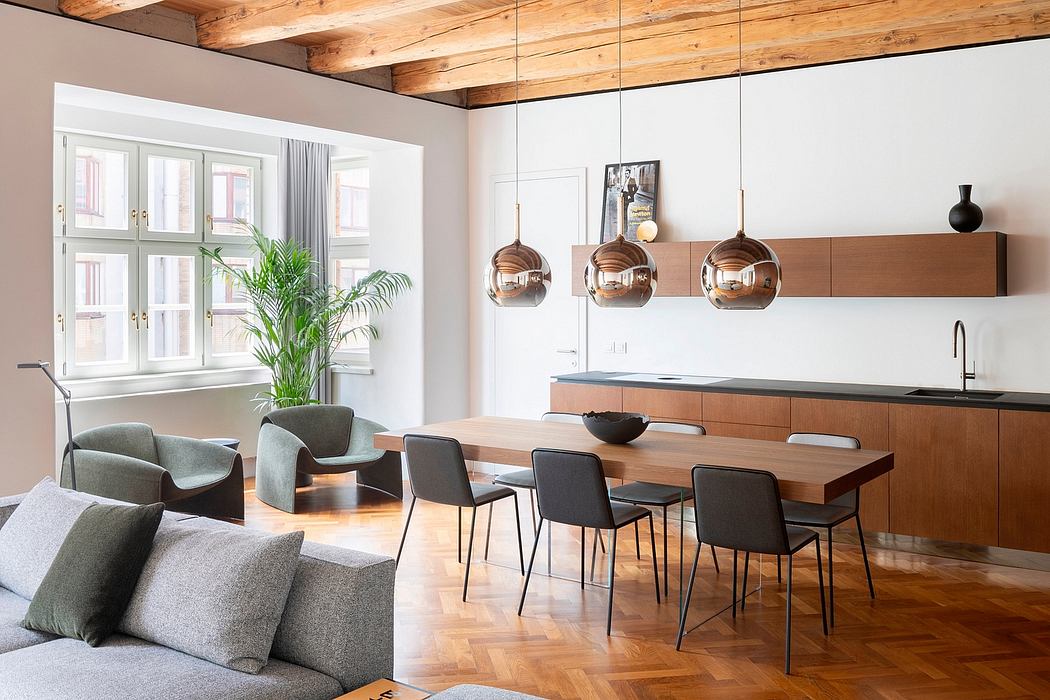 Modern open-plan living space with wooden beams, sleek furniture, and copper pendant lights.